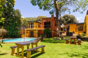 a house with a pool and benches in the yard at Linden Guest House in Johannesburg