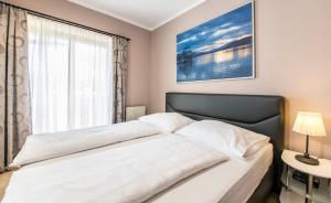 a bedroom with a large white bed with a window at Appartements Allmaier in Pörtschach am Wörthersee