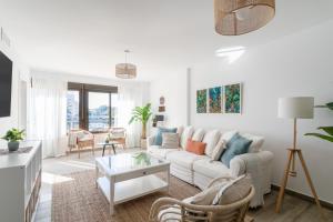 ein weißes Wohnzimmer mit einem Sofa und einem Tisch in der Unterkunft Costa Blanca Holiday Rental AltaMar II in El Campello