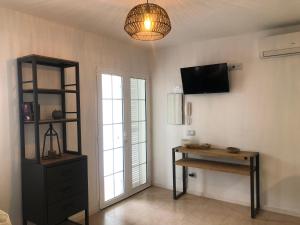 a room with a desk and a tv and a window at Acogedora casa unifamiliar junto a la playa in Cala en Bosc