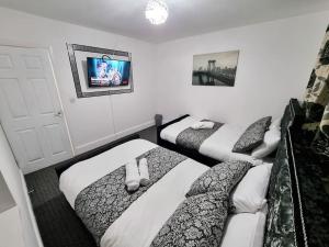 a room with three beds and a tv at nc23, setup for your most amazing & relaxed stay + Free Parking + Free Fast WiFi in Farnley
