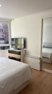 um quarto branco com uma cama e um espelho em Alojamiento Pichi em Vigo