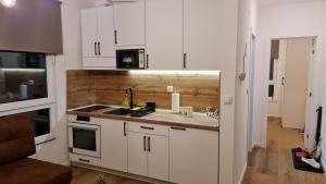 a kitchen with white cabinets and a sink at Wood Apartmani - Vila Zimska idila Jahorina in Jahorina