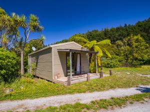 a small cabin on a beach with palm trees at Bay Cottage - Takaka Holiday Unit in Takaka