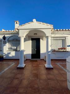 a white house with a black door and columns at Villa Tomillo in Málaga