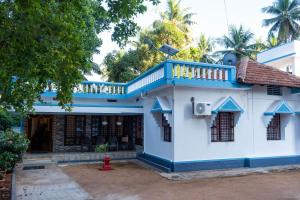 a blue and white house with a balcony at Reunion Pride Villa in Udupi