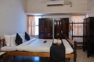 a bedroom with a bed with white sheets and blue pillows at Reunion Pride Villa in Udupi