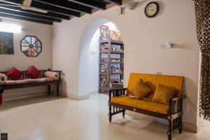 a living room with a yellow couch and a clock at Reunion Pride Villa in Udupi