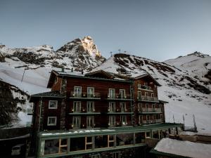 a building in front of a snow covered mountain at White Angel Hotel in Breuil-Cervinia