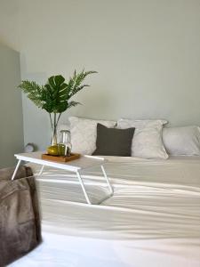 Una cama blanca con una mesa con una planta. en Runaway Bay The Vistas Townhome en Runaway Bay