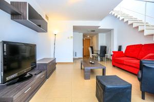 a living room with a red couch and a tv at Ciutadella Litoral - ONLY FAMILIES in Cambrils