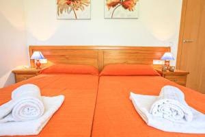 カンブリルスにあるSol Millet Litoral - ONLY FAMILIESの大きなオレンジ色のベッド(白いタオル2枚付)