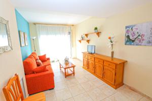 a living room with a red couch and a television at Sol Millet Litoral - ONLY FAMILIES in Cambrils