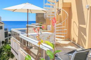 een balkon met een tafel en een parasol en de oceaan bij Austral - ONLY FAMILIES in Cambrils