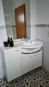 W białej łazience znajduje się umywalka i lustro. w obiekcie Apartment auf dem Hof einer historischen Mühle w mieście Holzhausen