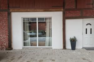 eine weiße Garagentür mit Fenster und Topfpflanze in der Unterkunft Apartment auf dem Hof einer historischen Mühle in Holzhausen