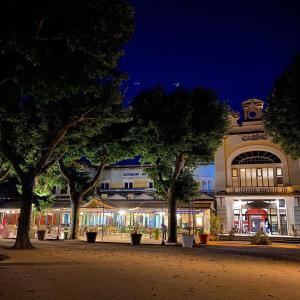 um edifício com árvores à frente à noite em La Dolce Vita Lucie em Vals-les-Bains