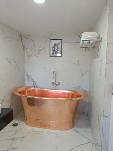 a copper tub in a bathroom with marble walls at Two Seas Residence in Ooty