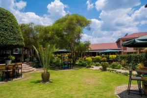 a garden with tables and chairs and a tree at Acacia Hotel Mbarara in Mbarara