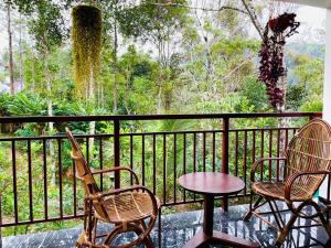 a balcony with two chairs and a table and a fence at WinterHome homestay in Munnar