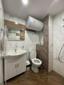 a bathroom with a white toilet and a sink at Апартамент Родопско мече in Devin