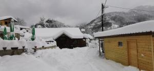 a snow covered house with a pile of snow next to it at Konak Šarac in Crni Vrh