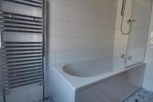 a white bath tub in a white tiled bathroom at Lovely Hudds home, x4 double bedrooms & parking in Huddersfield +14 photos