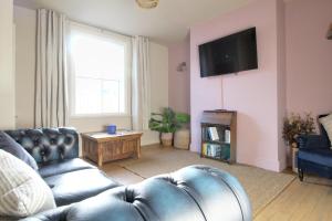 a living room with a couch and a flat screen tv at Lovely Hudds home, x4 double bedrooms & parking in Huddersfield