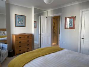 1 dormitorio con cama, tocador y espejo en Wren House, en Sidmouth