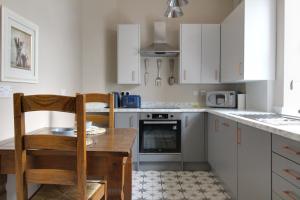 a kitchen with white cabinets and a wooden table and chairs at Lovely 4 Bed House in Huddersfield with parking in Huddersfield