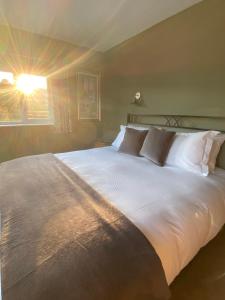 uma cama grande com lençóis brancos e almofadas num quarto em Marshpools Bed & Breakfast - Licensed near Weobley village em Weobley