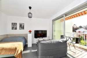 een slaapkamer met een bed, een tv en een balkon bij A La Plage et Au Soleil de St Palais sur Mer in Saint-Palais-sur-Mer
