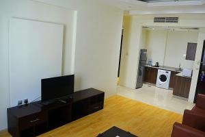 a living room with a flat screen tv and a kitchen at Palm Inn Hotel Doha in Doha