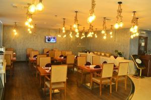 un restaurante con mesas de madera, sillas y lámparas de araña en Palm Inn Hotel Doha, en Doha