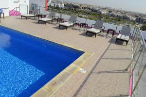 杜哈的住宿－Palm Inn Hotel Doha，一个带椅子的阳台和一个位于大楼内的游泳池