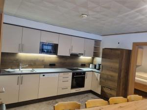 een keuken met witte kasten en een tafel en stoelen bij Haus Wildbach in Kappl