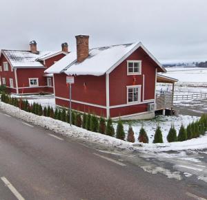 a red house on the side of a road with snow at Backes Lillstuga in Borlänge +15 photos