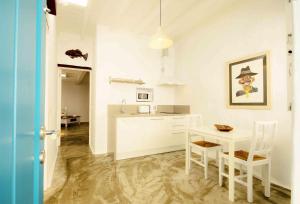 a white kitchen with a white table and chairs at La Casa de las Salinas in Punta Mujeres