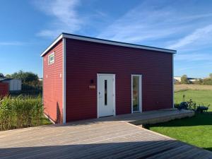 a small red building with a white door on a deck at Your own 30sqm house with kitchen, sauna and loft. in Malmö