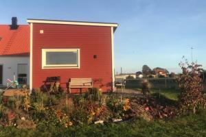 a red house with a bench next to a garden at Your own 30sqm house with kitchen, sauna and loft. in Malmö
