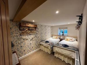 a bedroom with two beds and a wall covered in wallpaper at Cosy Alpine Cottage in the heart of Lancashire in Catterall