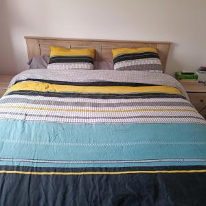 łóżko z niebiesko-żółtym kocem i dwiema poduszkami w obiekcie Maison pour location de chambre circuit 24H et GP w mieście Aigné