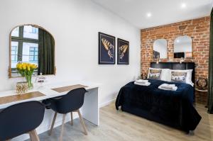 a bedroom with a bed and a desk with chairs at Apartamenty K&B Toruń in Toruń