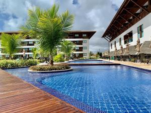 a resort swimming pool with palm trees and a building at Flat Resort Beira Mar Porto de Galinhas in Ipojuca