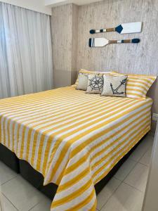 a yellow and white striped bed in a room at Cupe Beach Living Flat in Ipojuca