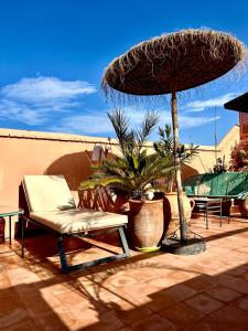 a patio with a chair and an umbrella and palm trees at Riad Lauriers Blancs in Marrakesh