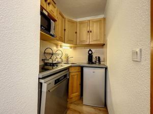 eine kleine Küche mit Holzschränken und einem Geschirrspüler in der Unterkunft Chaleureux appartement grand panorama 2 avec piscine au pied des pistes in Valmeinier