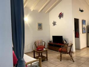 - un salon avec une télévision et deux chaises dans l'établissement Villa Florentine - Saint François - Guadeloupe, à Saint-François