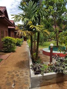 a garden with palm trees and a sidewalk at Phanyro Motel in Sen Monorom