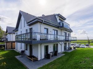 een groot wit huis met een balkon bij Meerblick mit Kamin am Saaler Bodden in Wustrow